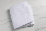 Clean folded towel on white marble table, top view