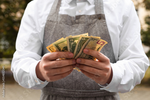 Waiter holding tips in outdoor cafe, closeup