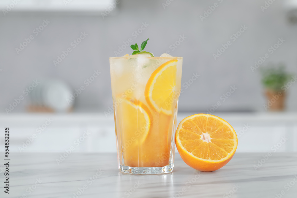Tasty refreshing drink with orange on white marble table in kitchen Tasty refreshing drink with orange on white marble table in kitchen