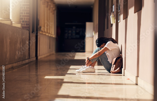 Sad, lonely and girl with depression at school, crying and anxiety after bullying. Mental health, tired and unhappy student in the corridor after problem in class, education fail and social isolation