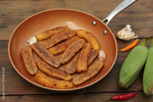 Delicious fried bananas, fresh fruits and different peppers on wooden table