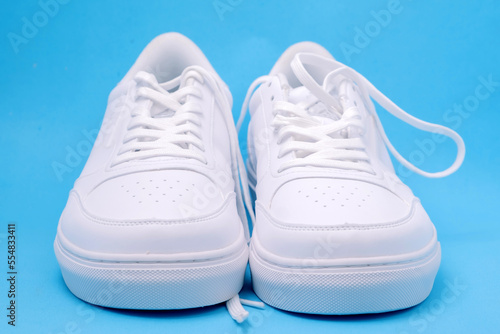 A pair of white sneakers on a blue background, flat lay