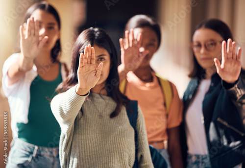 Woman, student and hands in stop for protest, enough or team standing for human rights or women empowerment. Group of female students with raised hand in halt, unity or strike for safe education