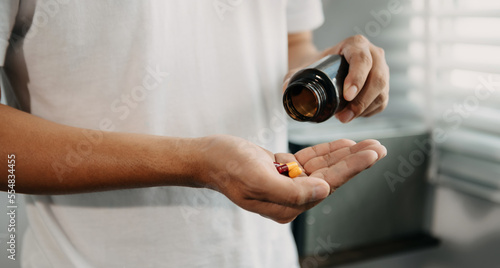 man with glass of water and pills on hand going to take medicaments prescribed by his physician.