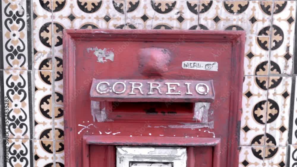 A zoom in of a traditional red mailbox on a tile facade in Lisbon, Portugal A zoom in of a traditional red mailbox on a tile facade in Lisbon, Portugal