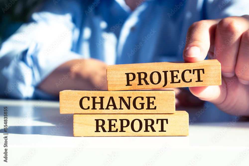 Closeup on businessman holding a wooden blocks with text PROJECT CHANGE REPORT, business concept Closeup on businessman holding a wooden blocks with text PROJECT CHANGE REPORT, business concept