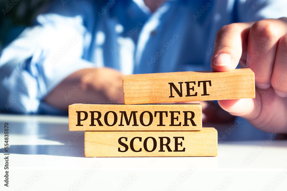 Closeup on businessman holding a wooden blocks with text NET PROMOTER SCORE, business concept Closeup on businessman holding a wooden blocks with text NET PROMOTER SCORE, business concept
