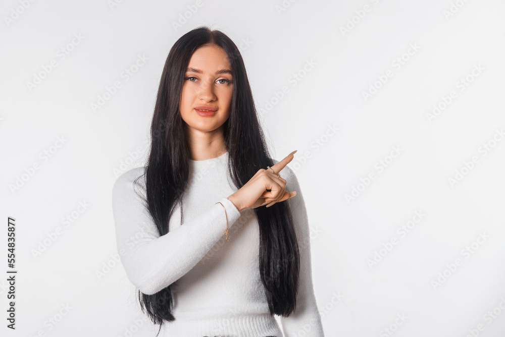 Confident young woman pointing finger aside and up, showing advertisement. Portrait of serious student, secretary, girl, female over white studio background. Copy space Confident young woman pointing finger aside and up, showing advertisement. Portrait of serious student, secretary, girl, female over white studio background. Copy space