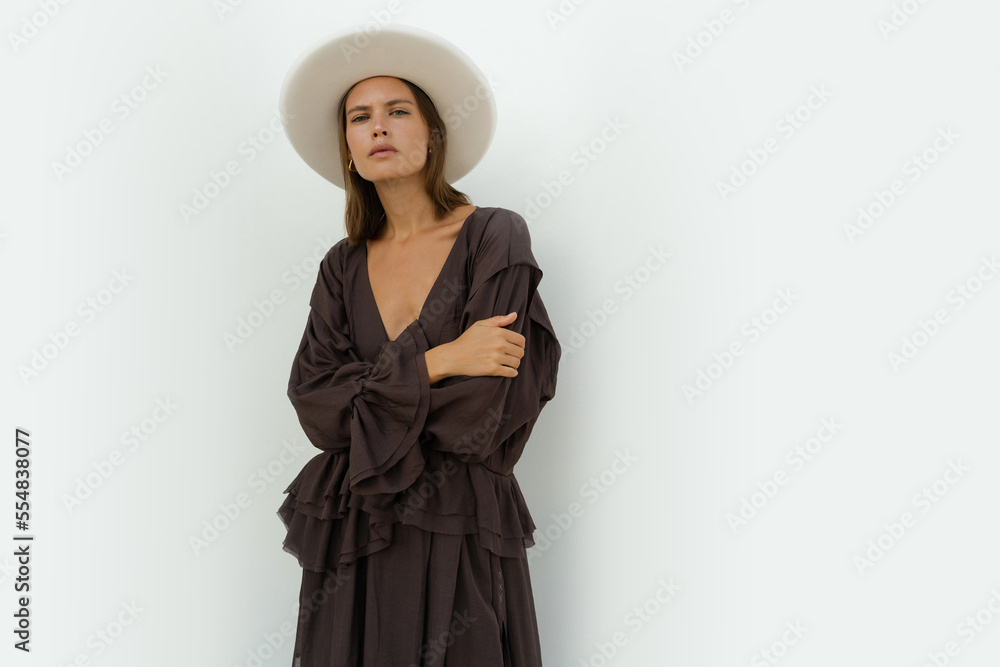 Fashion model in stylish white field proper hat and trendy casual dress posing in studio on white background. Fashion model in stylish white field proper hat and trendy casual dress posing in studio on white background.