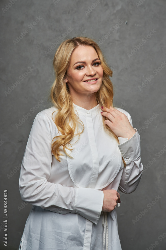 Studio beauty portrait of a young woman in a summer dress. Blond female in a summer dress posing over gray background. Studio beauty portrait of a young woman in a summer dress. Blond female in a summer dress posing over gray background.