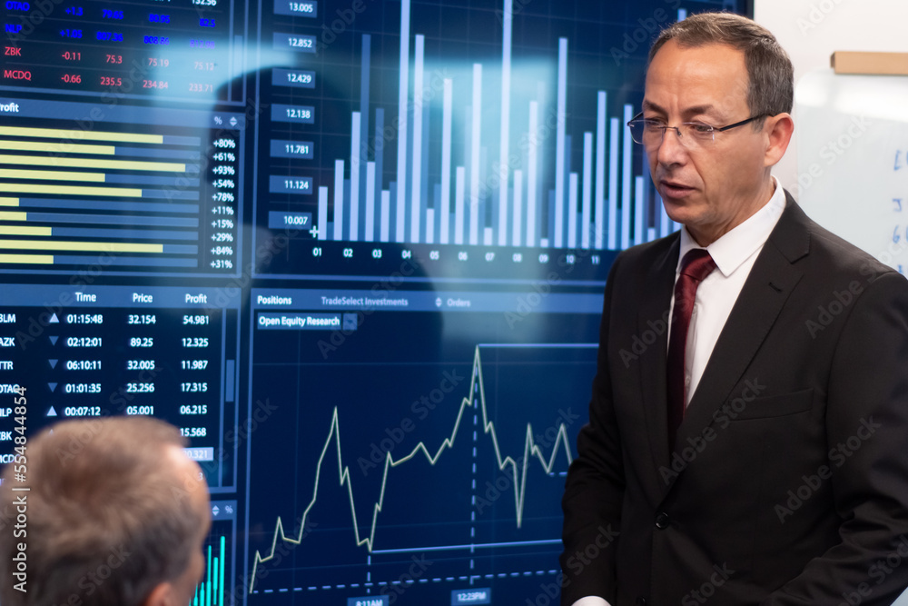 Portrait of serious managers discussing charts. Two confident men in workflow looking at digital screen with financial data analyzing prices growth. Business growth, financial analytics concept Portrait of serious managers discussing charts. Two confident men in workflow looking at digital screen with financial data analyzing prices growth. Business growth, financial analytics concept