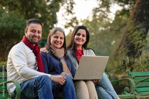 Indian or asian people in warm wear and using laptop at park