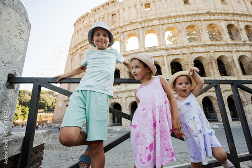 Photography Three funny kids against Colosseum in the old city center of Rome, Italy