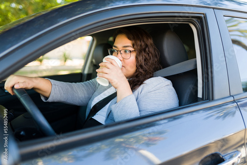 Busy overweight woman driving and drinking coffee