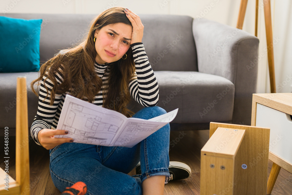 Obraz premium Stressed woman assembling furniture having problems