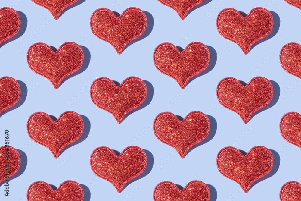 Pattern made from glitter heart shape on colored background with hard shadow. Valentines day minimalistic design