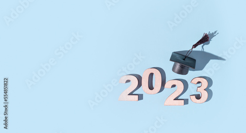 Class of 2023 concept. Numbers 2023 with black graduated cap on colored background