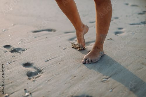 Close-up of childs feet in sand, at sea.