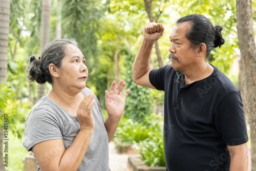 Angry old husband trying to punch his senior wife, concept of senior couple with regular fight and domestic violence