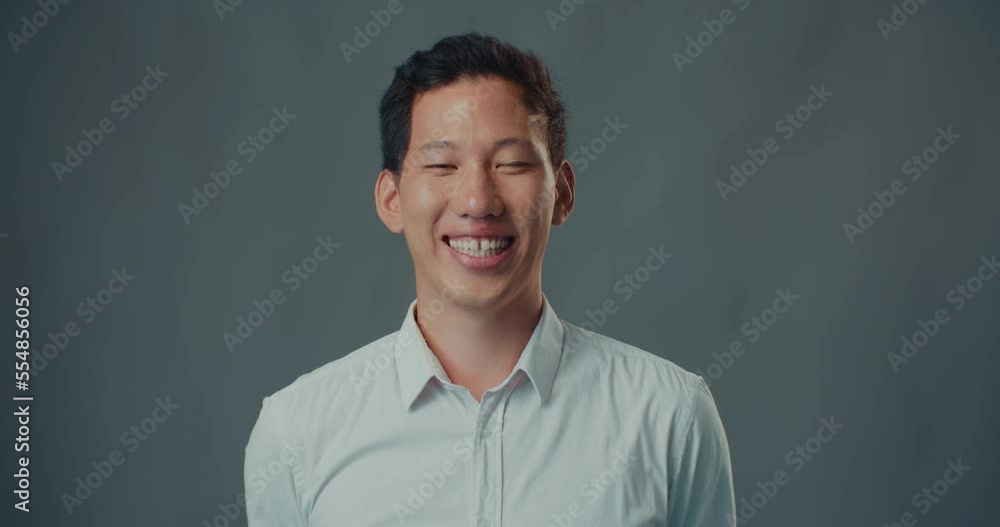 Portrait of young happy Asian male student, businessman cheerfully smiling at camera isolated at gray background. Portrait of young happy Asian male student, businessman cheerfully smiling at camera isolated at gray background.