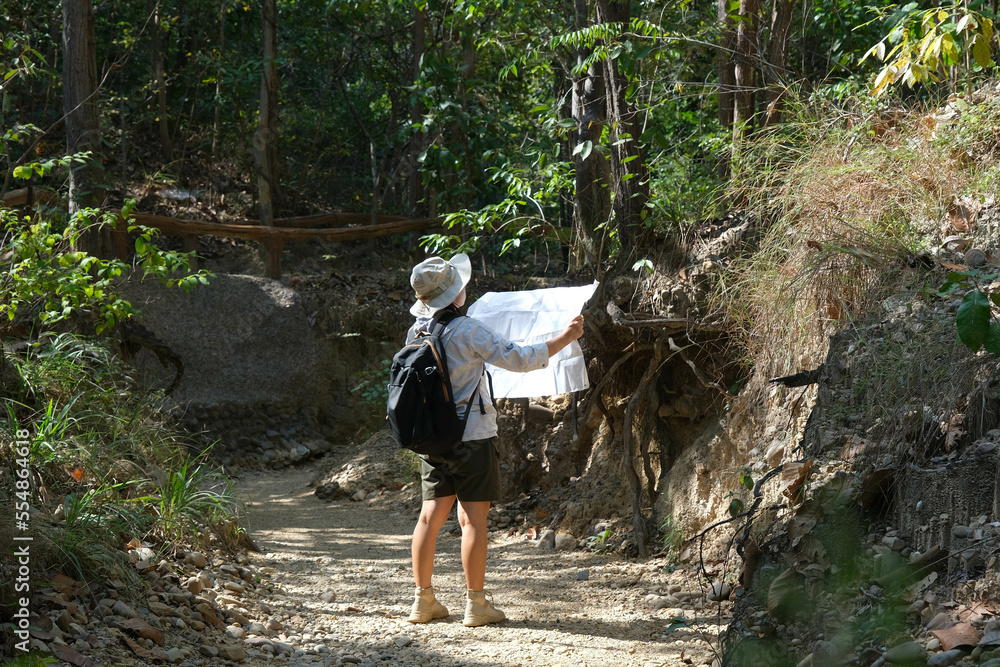 Female geologist using a map, examining a natural path and analyzing rocks or gravel. Researchers collect samples of biological materials. Environmental and ecology research. Female geologist using a map, examining a natural path and analyzing rocks or gravel. Researchers collect samples of biological materials. Environmental and ecology research.
