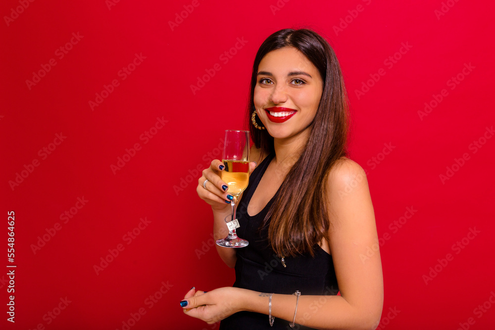 Smiling attractive girl with wonderful smile and long dark hair posing at camera with glass of wine. Celebration, holidays, new year, birthday Smiling attractive girl with wonderful smile and long dark hair posing at camera with glass of wine. Celebration, holidays, new year, birthday