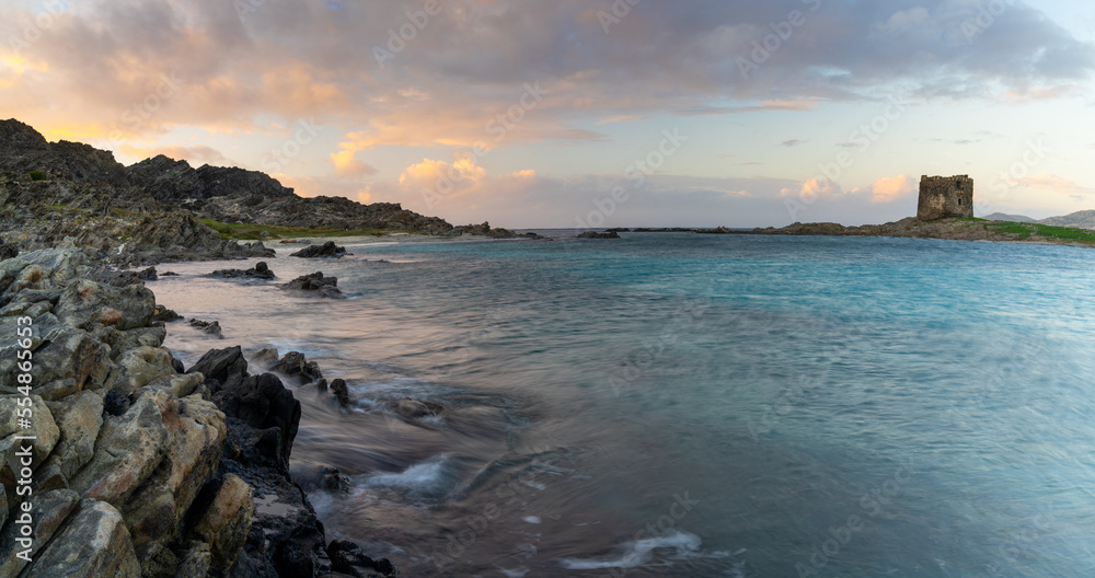 panorama landscape with rocky shore at sunset and the Torrre de la Pelosa watchtower in northern Sardinia