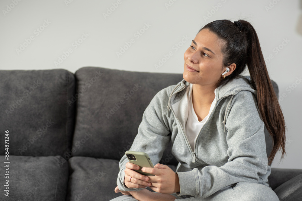 girl in grey tracksuit on the sofa with mobile phone girl in grey tracksuit on the sofa with mobile phone