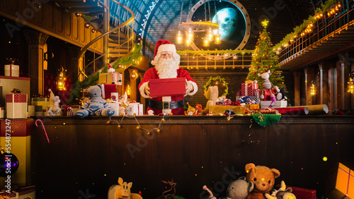 Wide Shot of Santa Claus in His Studio Workshop: Wrapping and Packing Christmas Gifts for all the Good Children to be Delivered on the Magical New Year Eve. He Prepares the Gifts this Winter Holiday