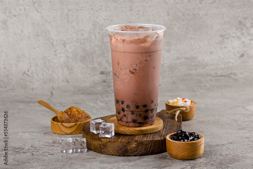 Boba or tapioca pearls is taiwan bubble milk tea in plastic cup with dark chocolate flavor on texture  background, summers refreshment.