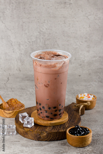 Boba or tapioca pearls is taiwan bubble milk tea in plastic cup with dark chocolate flavor on texture  background, summers refreshment.