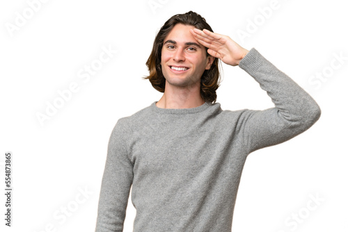 Young caucasian man isolated on green chroma background saluting with hand with happy expression