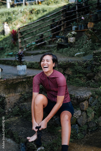 A young female cyclist is putting on her cycling shoes to get ready for a bike ride in the mountains.