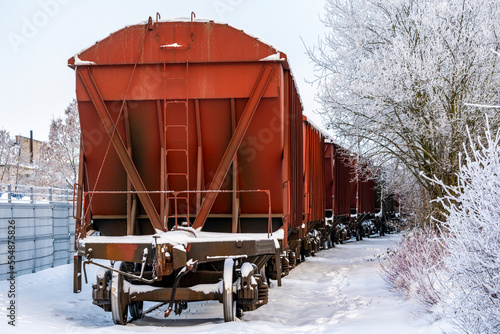 Carriages of a cargo train rides through a snow covered railway line
