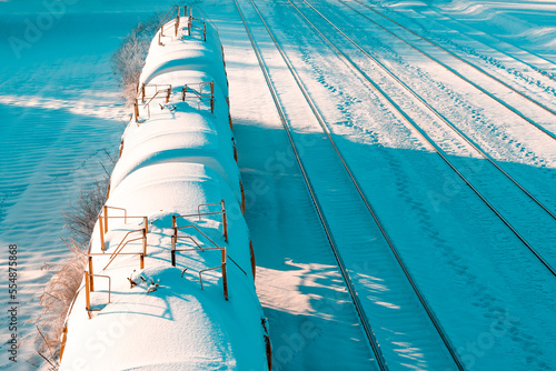 Snow covered tank-wagons of the cargo train standing on the railway