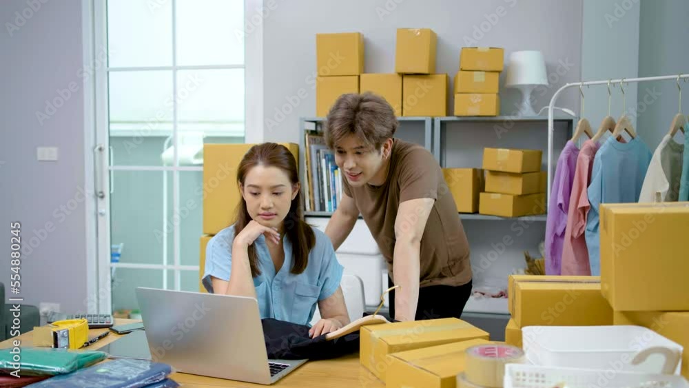 Young Asian couple business working in simple house office look like doing startup business and check store order by laptop, Surprise of couple success on making big sale of his online store.