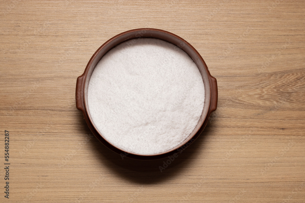 Brown container with white salt for seasoning. Salty concept on wooden table Brown container with white salt for seasoning. Salty concept on wooden table