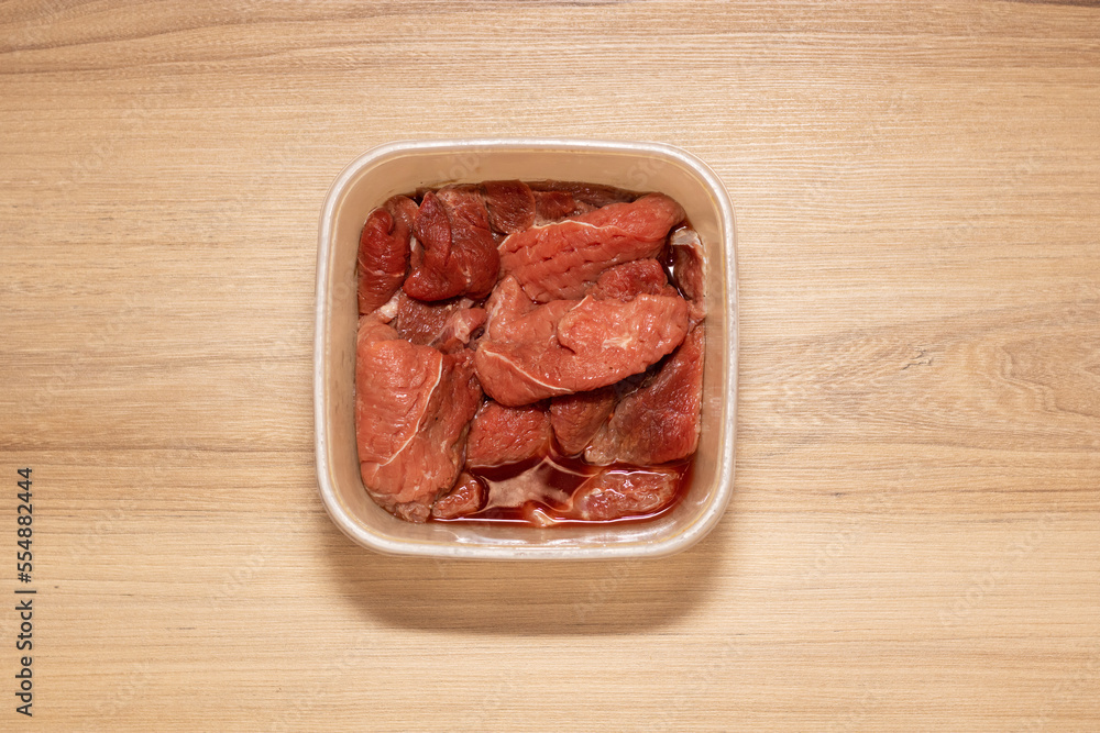Raw meat in transparent container. High quality photo with beef meat on wooden table