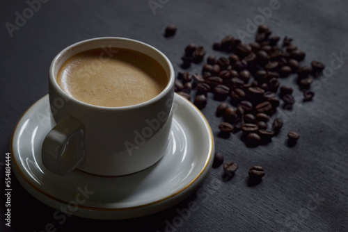 Hot cappuccino and coffee beans on a dark background