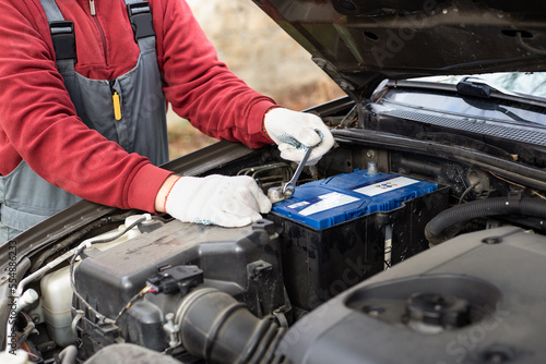 mechanic replaces the car battery. Discharging the battery and repairing the car