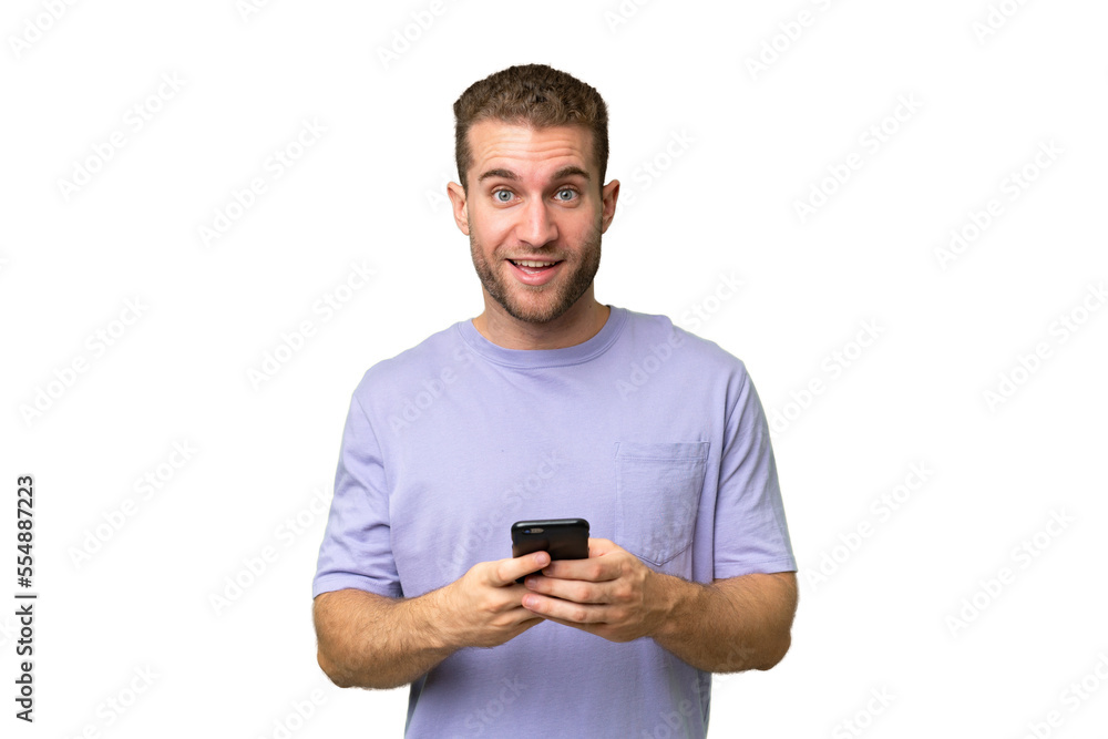 Young handsome caucasian man isolated on green chroma background surprised and sending a message Young handsome caucasian man isolated on green chroma background surprised and sending a message