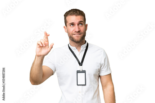 Young caucasian man with ID card isolated on green chroma background with fingers crossing and wishing the best © luismolinero