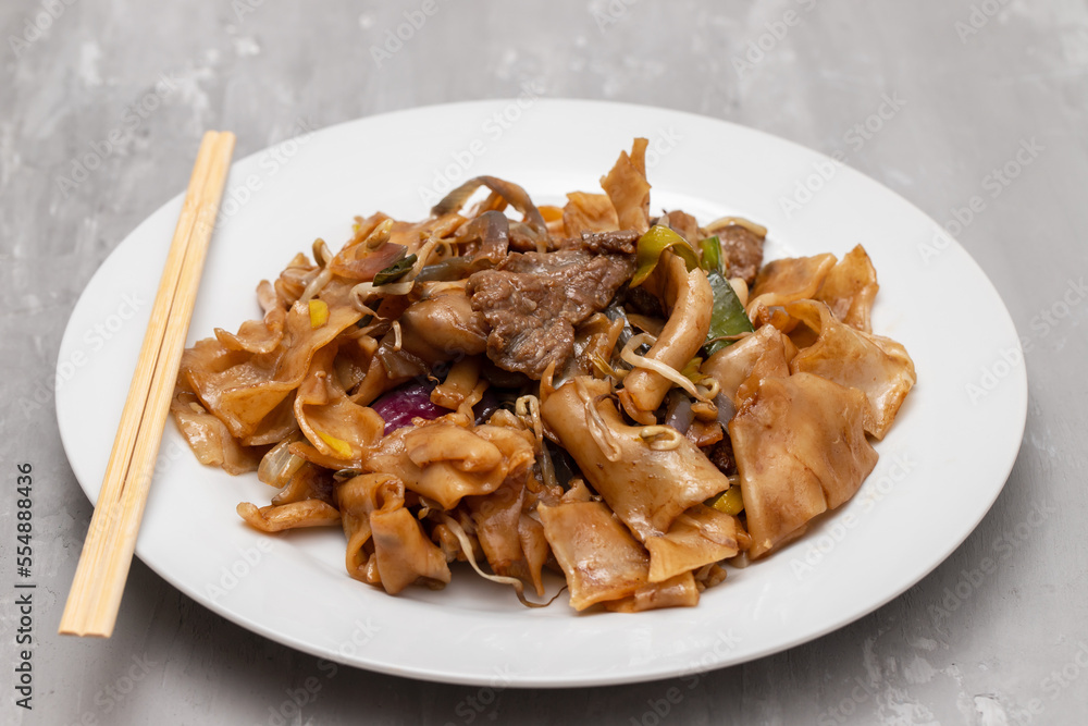 Fried noodles with vegetables and beef in white dish Fried noodles with vegetables and beef in white dish