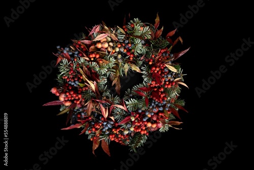 Modern christmas wreath on black background. Rustic christmas wreath with fir branches, berries and cone. Merry Christmas