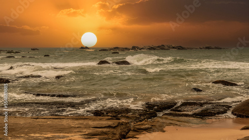 Fototapeta Naklejka Na Ścianę i Meble -  beautiful sunset over the ocean with rocks in the foreground