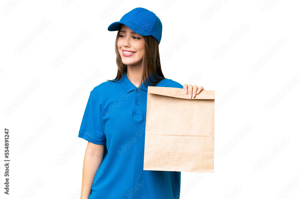Young beautiful caucasian woman taking a bag of takeaway food over isolated background looking to the side and smiling Young beautiful caucasian woman taking a bag of takeaway food over isolated background looking to the side and smiling