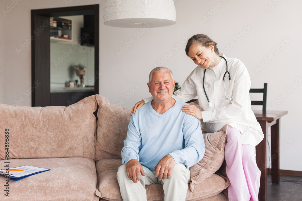 Female professional doctor showing medical test result explaining prescription using clipboard visiting senior elderly old man patient at home sitting on sofa Female professional doctor showing medical test result explaining prescription using clipboard visiting senior elderly old man patient at home sitting on sofa