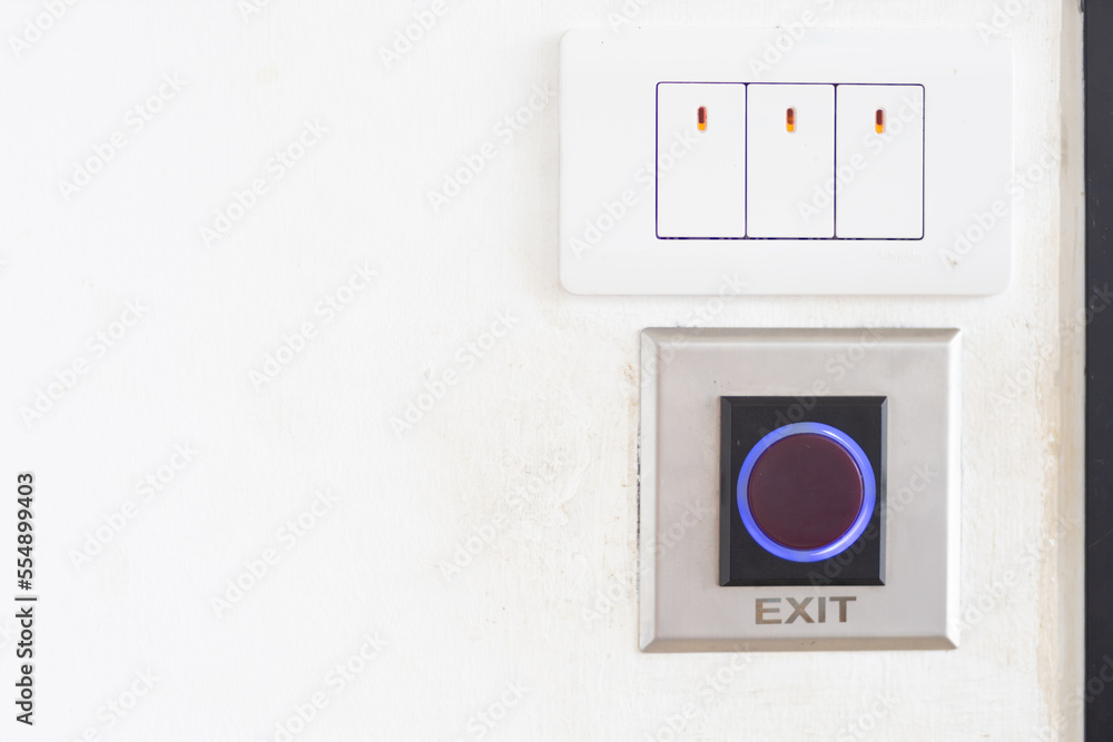 Close up of the light switch and exit button on the wall next to the door. Close up of the light switch and exit button on the wall next to the door.