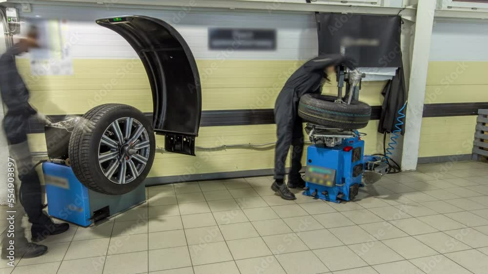 Professional car mechanic replace tire on wheel in auto repair service timelapse. Next mechanic balancing wheel with machine balancer at service.