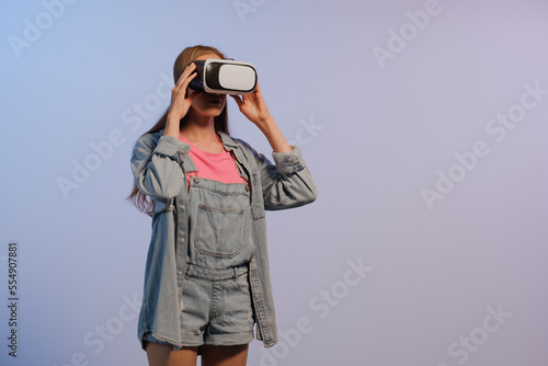 VR virtual reality glasses on a girl. Looks to the future. Touching the new. Fantastic virtual world. The emotion of immersion, surprise, indignation, fright, fear, laughter, delight. NFT concept.